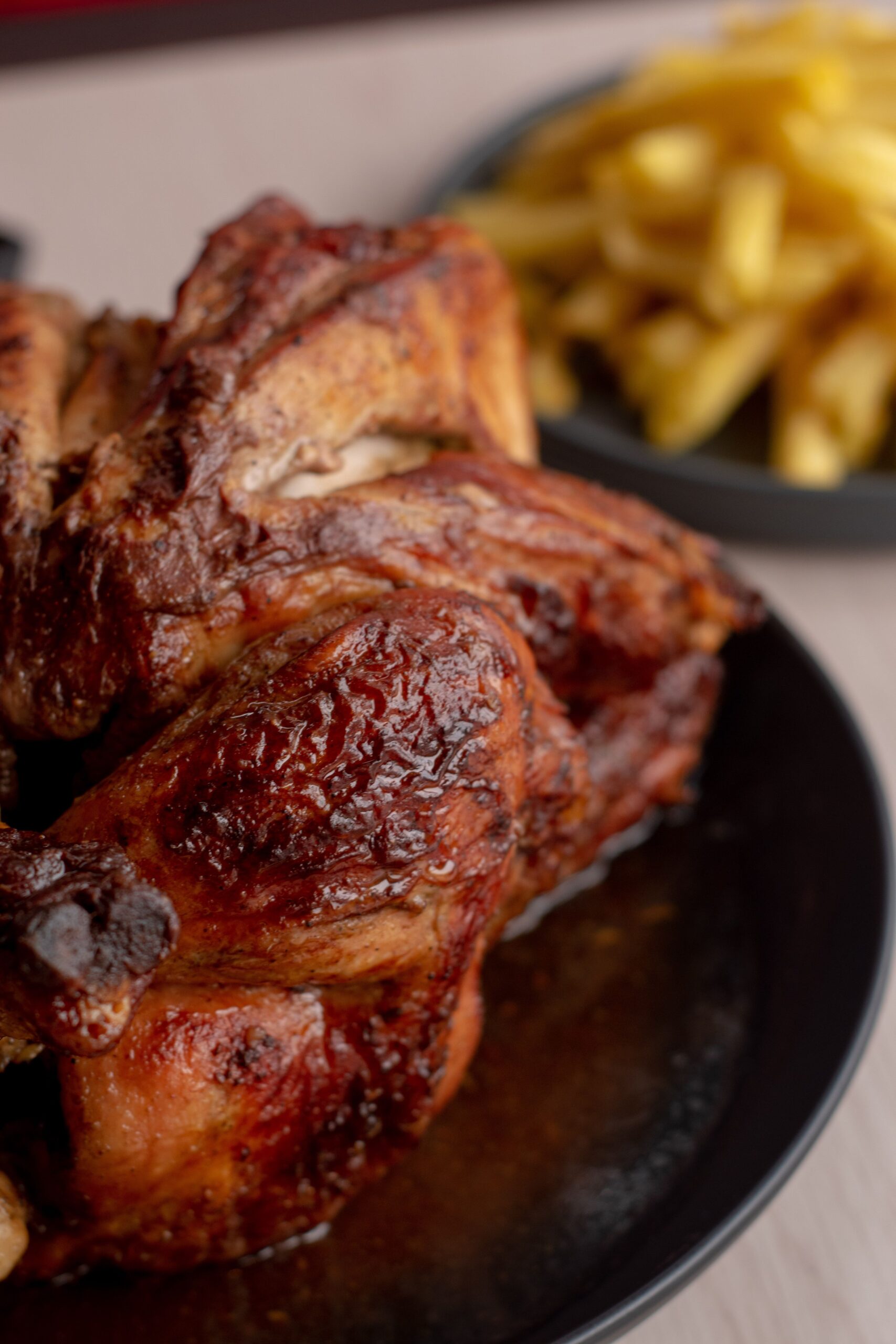 Delicious roasted chicken served with crispy golden fries on a dark plate.