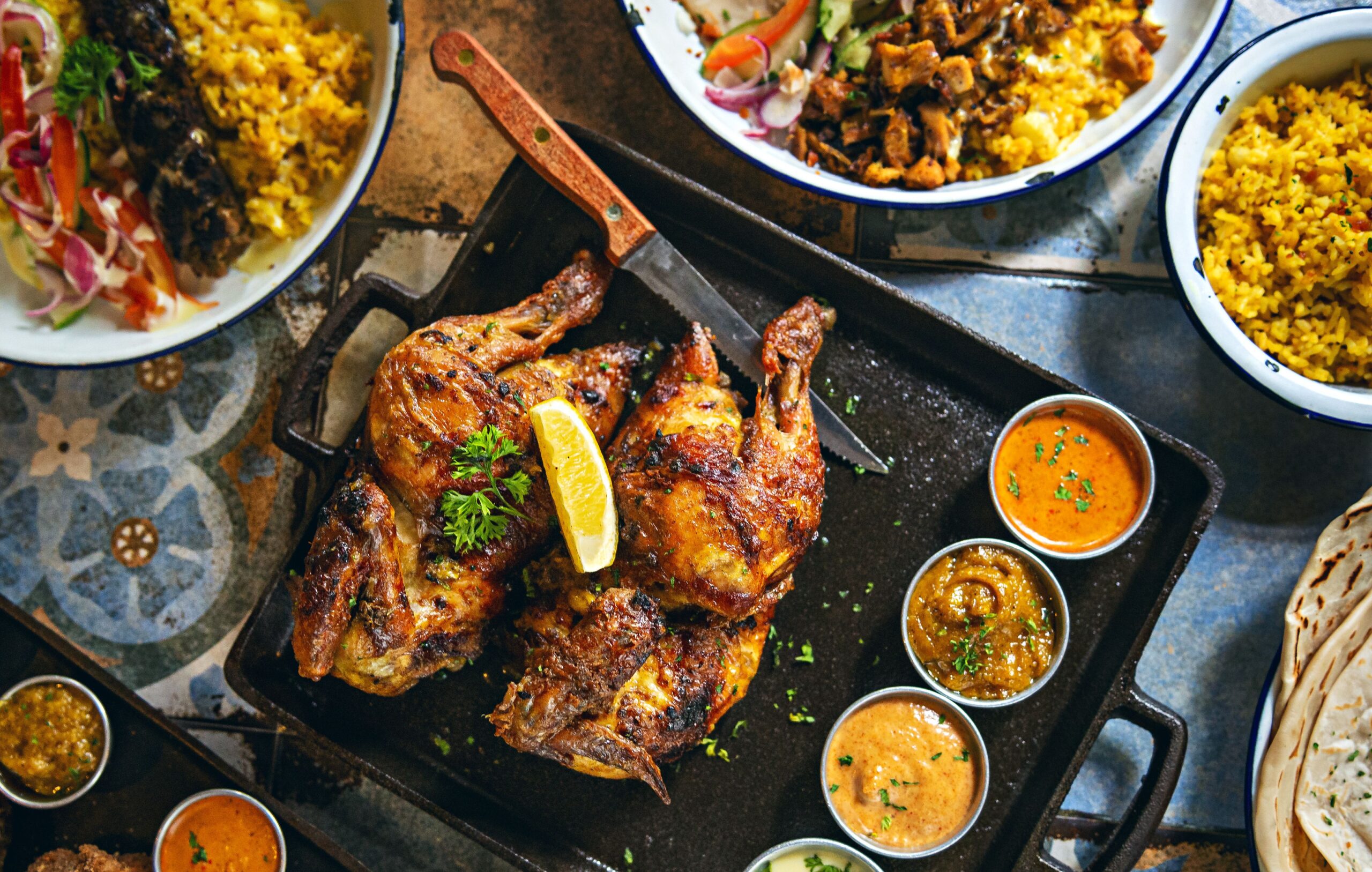 Grilled chicken with lemon, served on a tray with sauces. Perfect for food photography.